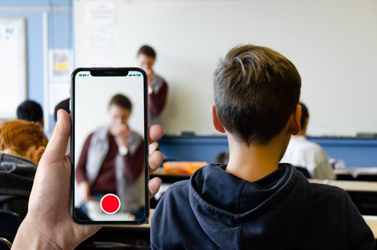 Schüler filmt mit Handy Lehrer im Klassenraum
