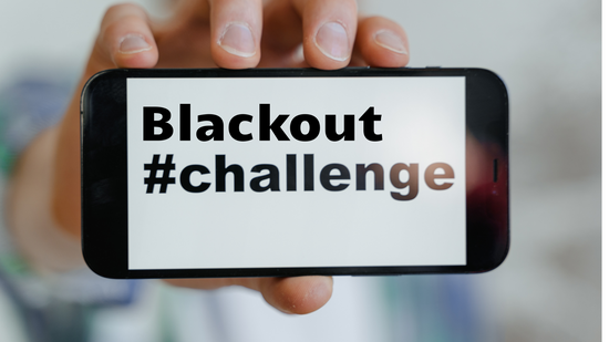 Ein junger Mensch, der Handy mit #Blackout-Challenge Schriftzug in der Hand hält