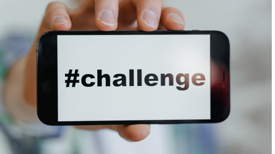 Challenge Canva von_MART_PRODUCTION_von_Pexels_an Ein junger Mensch, der Handy mit #Challenge Schriftzug in der Hand hält