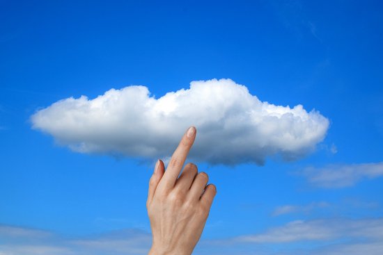Eine weiße Wolke im blauen Himmel. Ein Finger zeigt auf/berührt sie