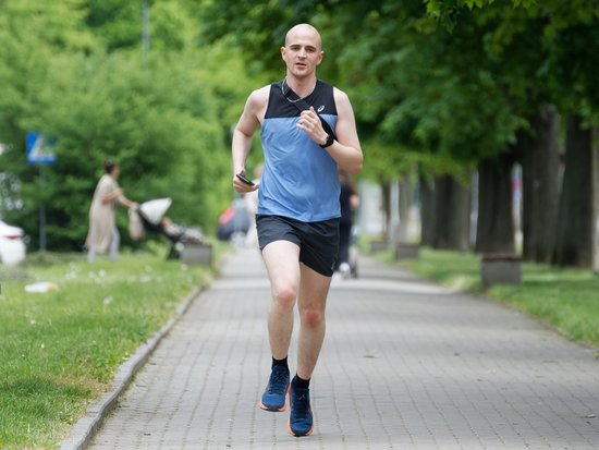 Ein Jogger draußen auf einem Gehweg in einer Alle im Park