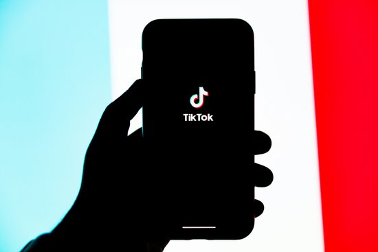 Die App Tiktok geöffnet vor der französichen Flagge