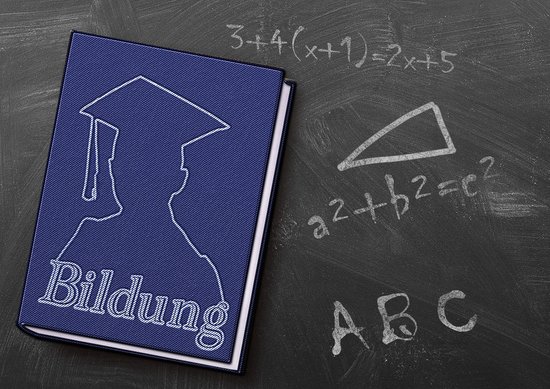 Eine Tafel mit Formeln und einem Buch darauf liegend mit dem Titel "Bildung"