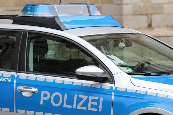Bild vom vorderen Teil eines blauen Polizeiauto. Blickpunkt ist von außerhalb in Richtung Beifahrertür