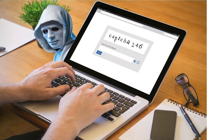 Eine Person, die am Computer ein CAPTCHA ausfüllt und dabei schaut ihr ein Hacker zu.