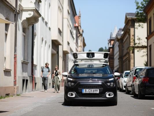 Auto mit Kamera auf dem Dach und Berliner Kennzeichen in Häuserschlucht